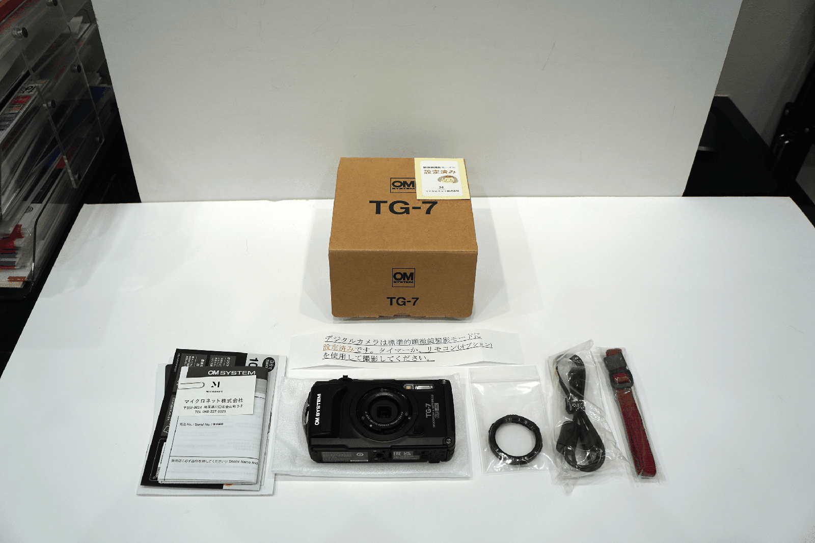 茶色の箱の中身。保証書、TG-7カメラ本体、マウント用のカバー、USBケーブル、ストラップ